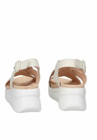 Sandali bianchi con tacco spesso, caratterizzati da cinturini incrociati, una chiusura con fibbia e una texture liscia e opaca. Soletta morbida beige.