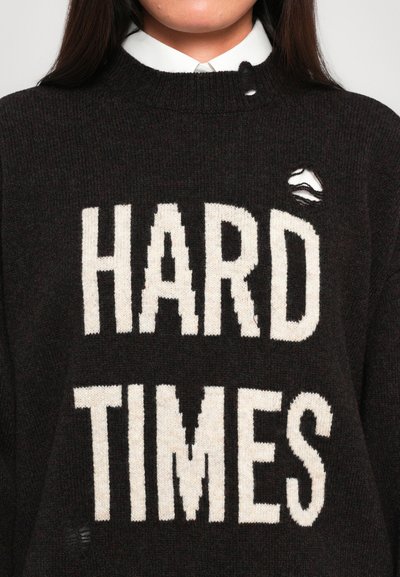 Black knitted sweater featuring the text "HARD TIMES" in white, with a small hole on the upper right side. Round neckline.