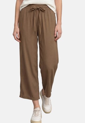 Brune bukser med vide ben og bindebånd foran i taljen, båret med hvide sneakers, kombineret med en tekstureret hvid top.