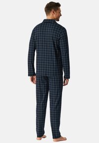 Conjunto de pijama azul marino con un patrón de cuadros, hecho de tejido suave. Presenta una parte superior de manga larga y pantalones a juego, con un ajuste relajado.