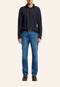 Laevastiku pikkade varrukatega polo, sinised teksapüksid, must vöö, pruunid kingad. Lihtne disain, lõdvestunud istuvus, ühtlased värvid ja minimaalsed riistvaradetailid.