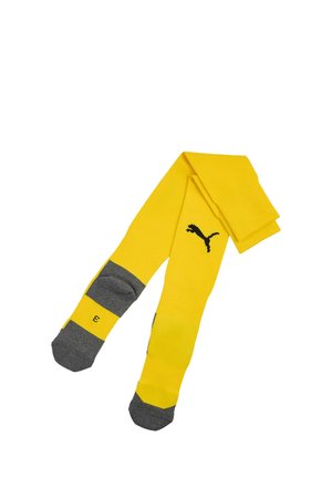 Calzini gialli al ginocchio con punta e tallone grigi, con logo Puma nero sul davanti e numero di taglia su un piede.