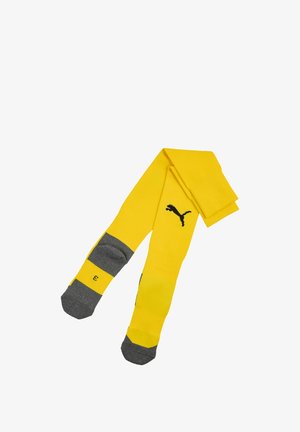 Calzini gialli al ginocchio con punta e tallone grigi, con logo Puma nero sul davanti e numero di taglia su un piede.