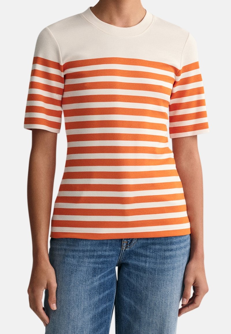 Camiseta a rayas en crema con rayas horizontales naranjas y blancas, de manga corta y escote redondo. El material parece suave y ligero.