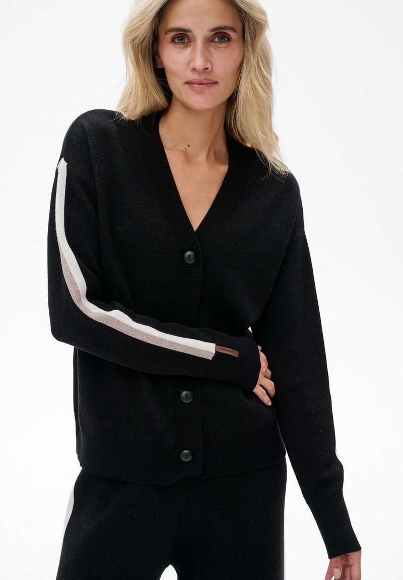 Zwarte cardigan met een V-hals, knoopsluiting en lange mouwen met een witte en beige streep langs de arm. Gebreide textuur met een subtiele glans.
