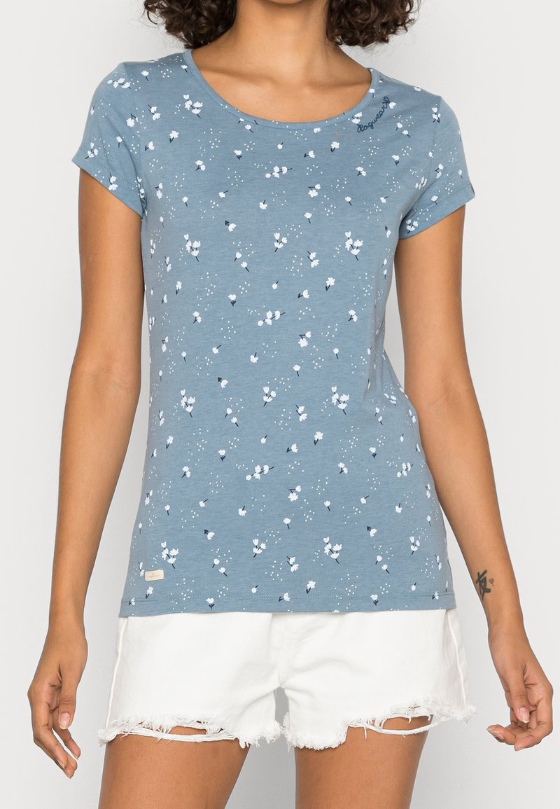 Jasnoniebieski t-shirt z krótkim rękawem z kwiatowym nadrukiem, przedstawiający białe i granatowe kwiaty, z okrągłym dekoltem i metką na dole.