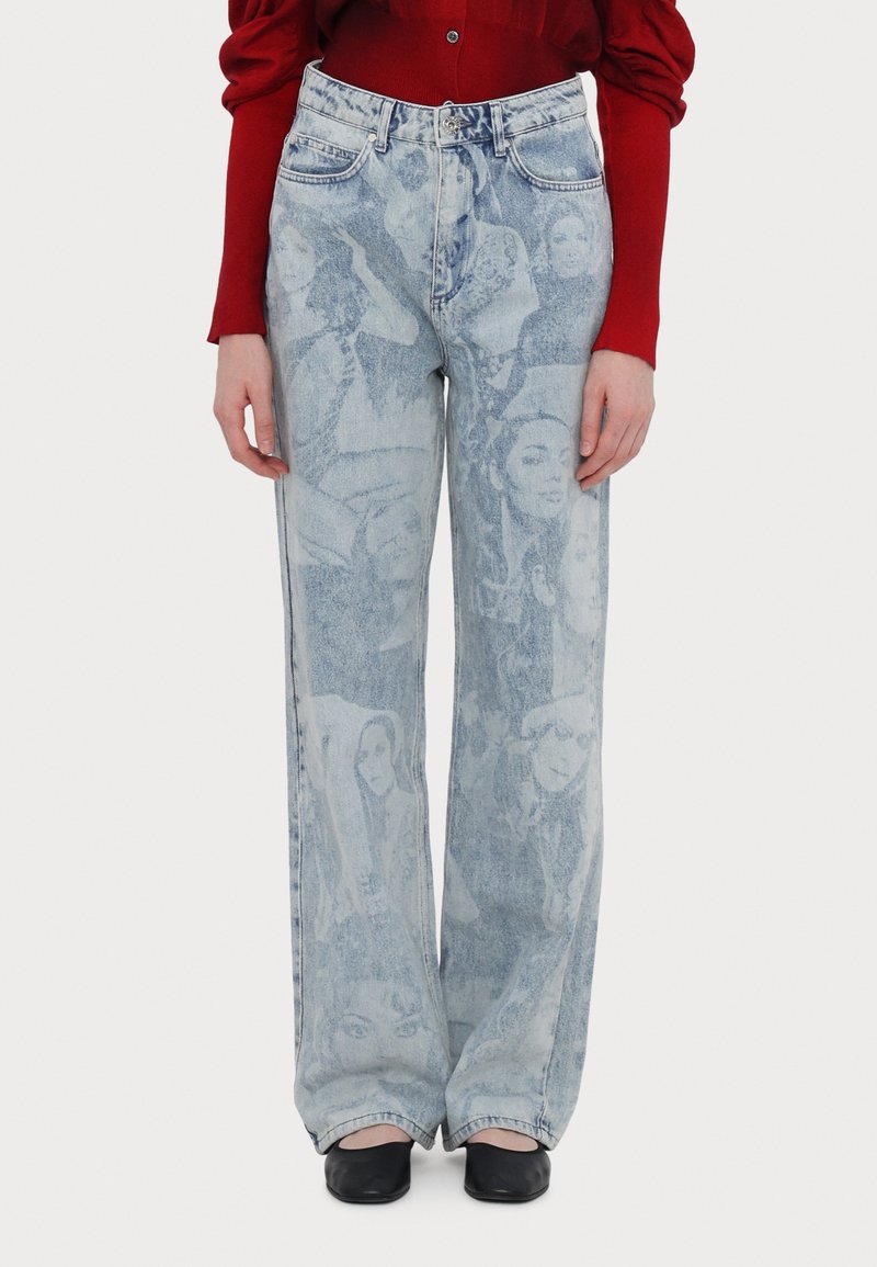 Světle modré džíny s širokými nohavicemi, zdobené vybledlým grafickým vzorem tváří, pěticí kapsami a kovovým zapínáním na knoflík.