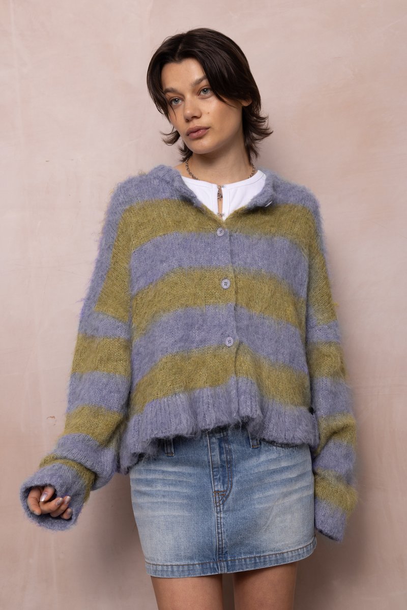 Csíkos kardigán puha, bolyhos fonalból; színei között szerepel a világoskék és az olíva zöld. Gombos záródással és rövidített szegéllyel rendelkezik.