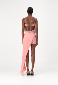 Pink lace dress with a sheer overlay, open back design, and a long flowing train. The fabric is lightweight and soft. Black strappy heels.