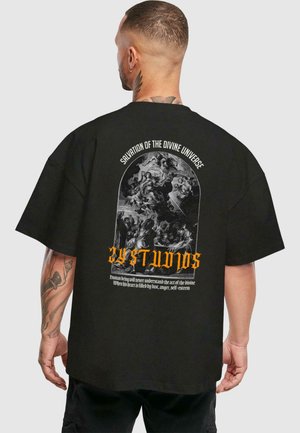Black oversized t-shirt featuring a graphic print on the back with intricate black and white imagery and bold orange text.