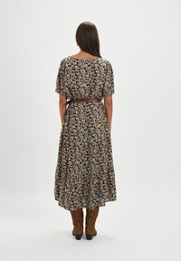 Kwiatowa sukienka wrap z krótkimi rękawami, na ciemnym tle, z pomarańczowym i białym wzorem kwiatowym, pasek w talii, brązowe zamszowe botki do kostek.