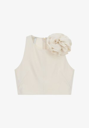Top corto beige senza maniche con un grande fiore di stoffa sulla spalla sinistra e chiusura con cerniera sul retro.