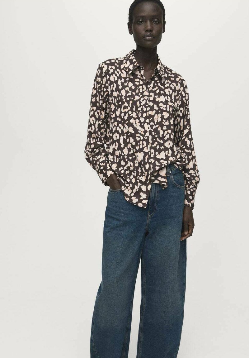 Cămașă cu mâneci lungi, maro închis, cu pete abstracte de leopard în bej deschis, asortată cu blugi largi de denim albastru, cu croială lejeră.