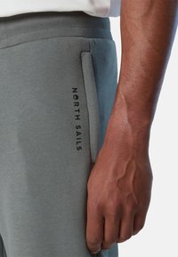 Graue Jogginghosen aus Baumwollmischung mit Seitentasche, versehen mit schwarzem "NORTH SAILS" Text. Ribbenbund für zusätzlichen Komfort. Glatte Textur.