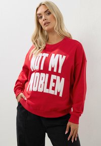 Felpa rossa con testo bianco e testurizzato "NON È UN MIO PROBLEMA". Presenta maniche lunghe, scollatura rotonda e una vestibilità comoda.