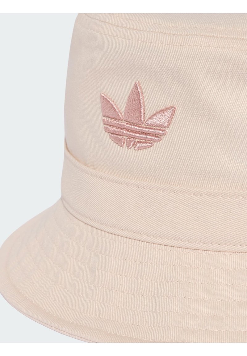Cappello bucket beige con logo rosa Adidas Trefoil cucito sul davanti, con cucitura visibile e tessuto strutturato.