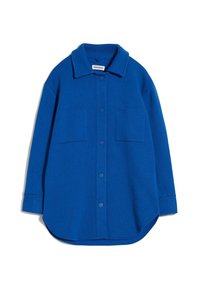 Blå ullskjorta med krage, två framfickor och knappstängning. Har en rundad nederkant och mjuk textur.