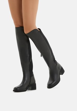 Schwarze kniehohe Stiefel aus glattem Leder mit Blockabsatz, ausgestattet mit einem seitlichen Reißverschluss und einem elastischen Einsatz für eine enge Passform.