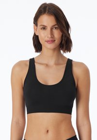 Reggiseno sportivo nero con scollo a U, spalline larghe, design senza cuciture e tessuto texture. Fornisce un elastico sottobusto per supporto.