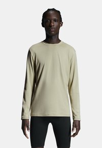 Lange mouw shirt in lichtbeige, gemaakt van gladde stof, met een ronde halslijn en rechte pasvorm, gecombineerd met zwarte shorts.