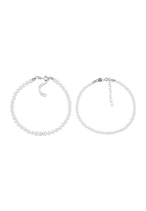 Twee delicate parelarmbanden met zilveren sluiting en verlengketting, naast elkaar geplaatst op een witte achtergrond.