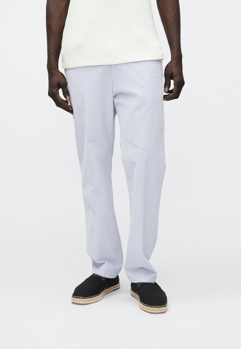 Vaaleansiniset, puuvillasekoitteesta valmistetut housut, joissa on väljä istuvuus, sivutaskut ja jotka on yhdistetty mustiin espadrillosaappaisiin. Sileä pinta.