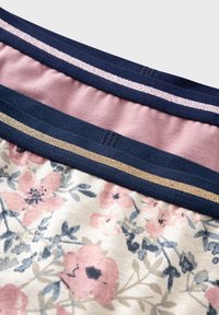 Tejido con estampado floral que presenta flores rosas sobre un fondo crema, bordeado por bandas elásticas en color azul marino y rosa con acentos metálicos.
