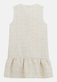 Ärmelloses Kleid aus leicht beigem, strukturiertem Stoff mit dezenten goldenen Fäden, das mit einem rüschengesäumten Saum und einem diskreten Reißverschluss auf der Rückseite ausgestattet ist.