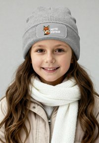 Gray ribbed beanie with a fox graphic patch, worn with a white textured scarf and light jacket. Features a snug fit and soft texture.