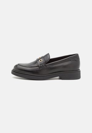 Mocassin en cuir noir avec un petit talon empilé, bout arrondi, et deux œillets dorés sur la bride passant sur le cou-de-pied, présenté de profil.