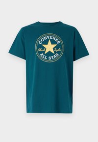 Camiseta de algodón de manga corta en color azul verdoso, con cuello redondo, que presenta un gran diseño gráfico de una estrella amarilla y el texto "Converse All Star".