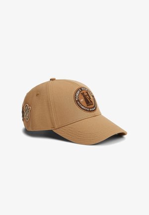 Beżowa czapka z daszkiem z okrągłą naszywką Tommy Hilfiger i wyhaftowanymi liczbami "1985" z boku, zakrzywionym daszkiem i materiałowym guzikiem na górze.