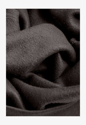 Donkergrijze stof met een zachte, gestructureerde oppervlakte, voorzien van gelaagde plooien en een geribbelde zoom. Het materiaal lijkt warm en gezellig.