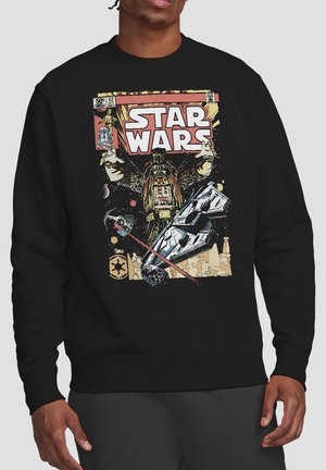 Man wearing black sweater featuring vintage-style Star Wars comic cover with Darth Vader, spaceships, and characters in space scene.
