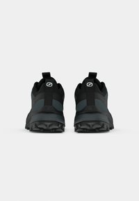 Zapatillas de trail running negras con una suela de goma texturizada, un refuerzo en el talón y una zona de puntera reforzada. Incluye tiradores en la parte trasera.