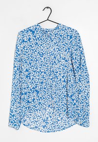 Blusa blu a maniche lunghe con motivo floreale caratterizzata da fiori bianchi, orlo arrotondato e chiusura con bottone al collo. Tessuto leggero.