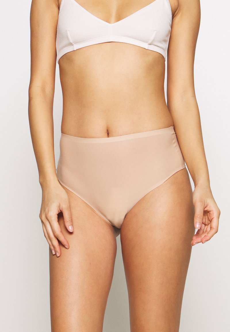 Bikini o wysokim stanie w kolorze nude, wykonany z gładkiego, elastycznego materiału. Posiada minimalne szwy i wygodny krój pasa.