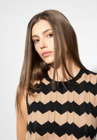 Gebreid top met een zigzagpatroon in zwart en beige, rond de hals en zonder mouwen. Gladde textuur en aansluitende silhouet.