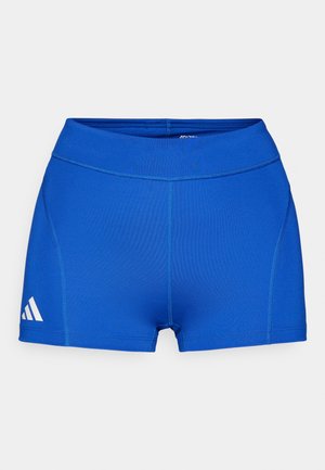 Shorts de sport bleus avec une texture lisse, dotés d'une large taille et d'un logo blanc sur le côté gauche. Les coutures sont bien visibles.