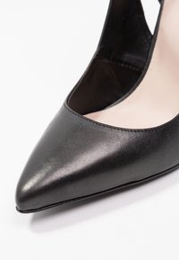 Černá kožená vysoká podpatek s špičatou špičkou a proříznutými stranami, s hladkým povrchem a minimem ševů.