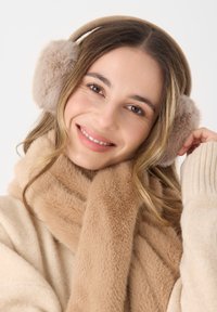 Beige Kunstfell-Ohrenwärmer mit einem Strickband, kombiniert mit einem passenden beigefarbenen Schal. Weiche Texturen und Farben schaffen einen gemütlichen Winter-Accessoire-Look.