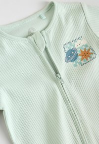 Mintgrön ribbad zip-up overall med en tecknad inspirerad grafik som föreställer en planet, sol och moln. Mjuk tyg med en strukturerad design.