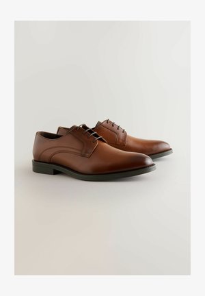 Chaussures habillées en cuir brun avec une texture lisse, bout rond, laçage à cinq œillets et une semelle en caoutchouc noir mince.