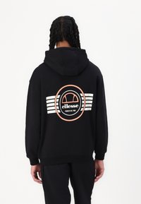 Svart hettegenser med et sirkulært logodesign i rosa og hvitt på baksiden, med horisontale striper som fremhever sidene.