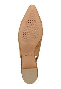 Zapato de tacón alto de ante beige con punta afilada y suela de goma texturizada que presenta perforaciones y un acento a rayas en el tacón.