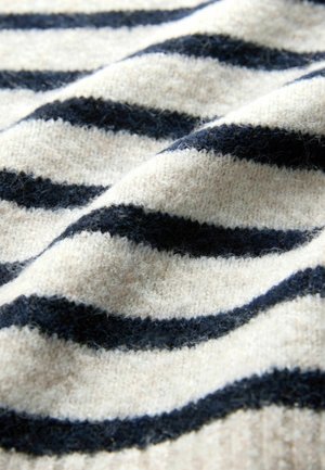 Ylletröjsmaterialet har växlande marinblå och krämfärgade ränder, med en mjuk, texturerad yta och lätt glans från fibrerna.