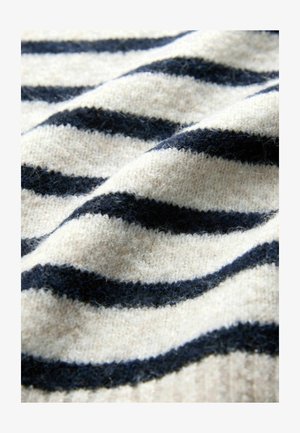 Ylletröjsmaterialet har växlande marinblå och krämfärgade ränder, med en mjuk, texturerad yta och lätt glans från fibrerna.