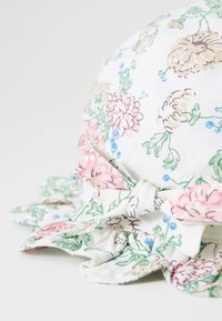 Sombrero de sol con estampado floral hecho de algodón, con un ala rizada, flores en colores pastel y un acento de lazo en el lateral.