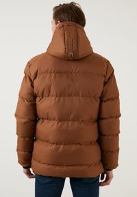 Brun pufferjakke med høj krave og justerbar hætte, der har lodrette quiltede sektioner og elastiske ærmer.