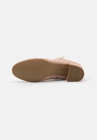 Beige Wildleder Slipper mit strukturiertem Gummi-Außensohle. Verfügt über eine abgerundete Form und minimale Akzente. Die Sohle zeigt rutschfeste Details.